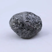 Close view of premium black diamond with bold dark sparkle and natural surface.