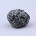 Close view of premium black diamond with bold dark sparkle and natural surface.