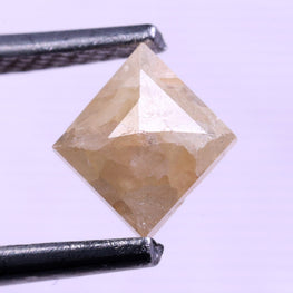 kite shape Diamond held between tweezers against a light purple background