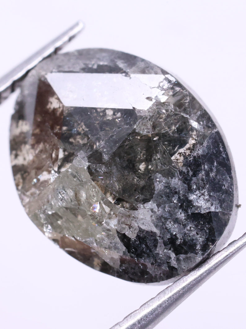 oval diamond held between tweezers on a light purple background