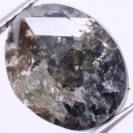 oval diamond held between tweezers on a light purple background