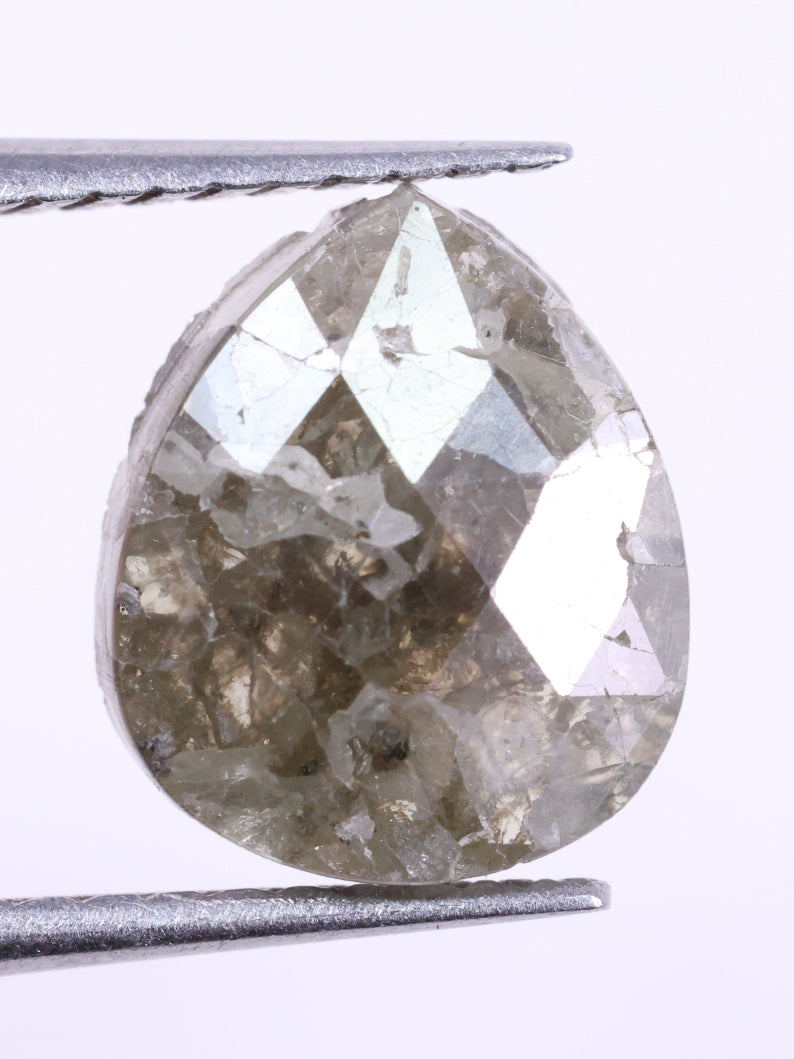 Teardrop-shaped diamond held between tweezers on a white background