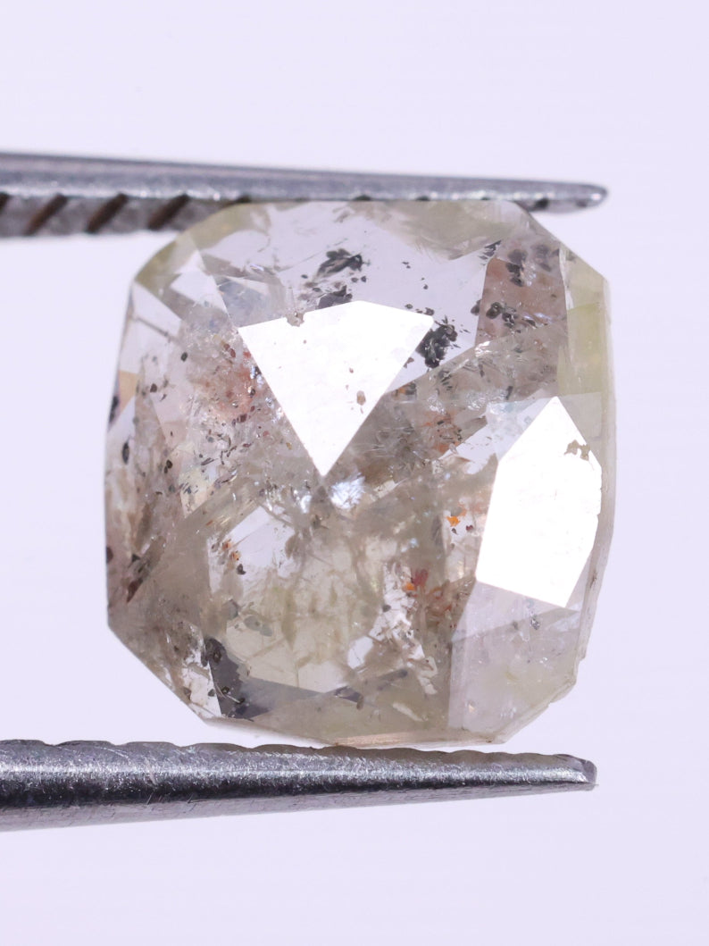 Diamond held between tweezers on a light purple background