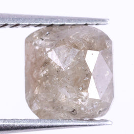 Cushion Cut diamond held between tweezers on a white background