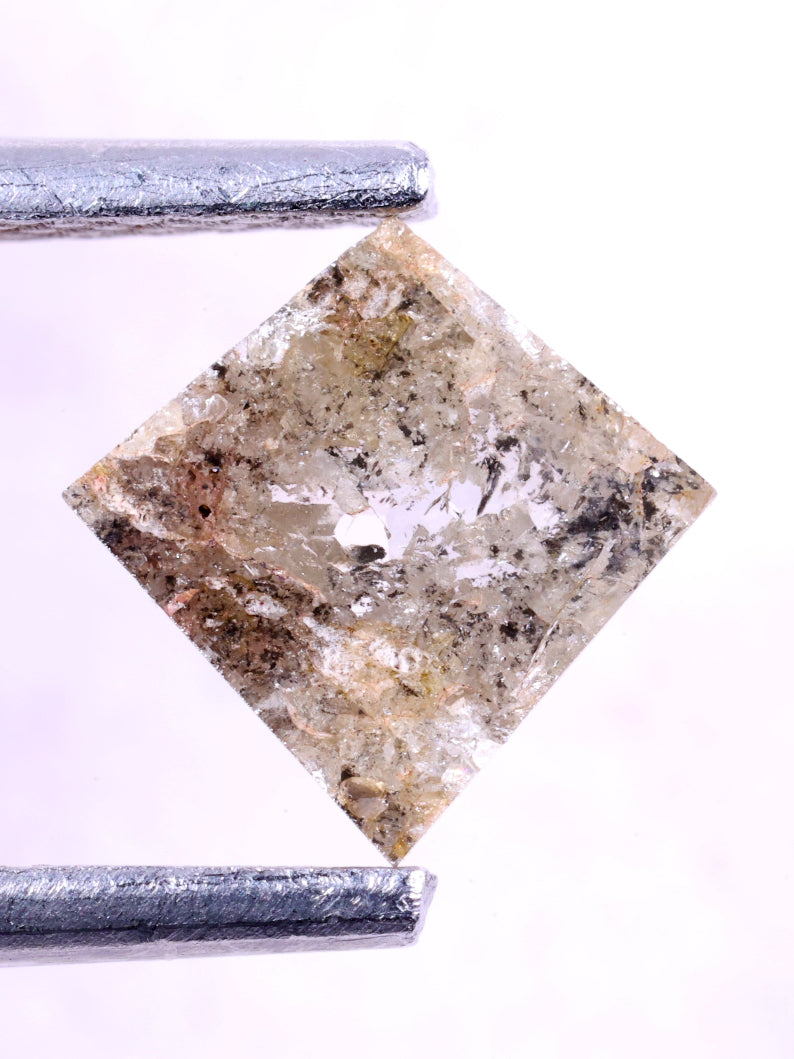 kite-cut diamond held between tweezers on a light background