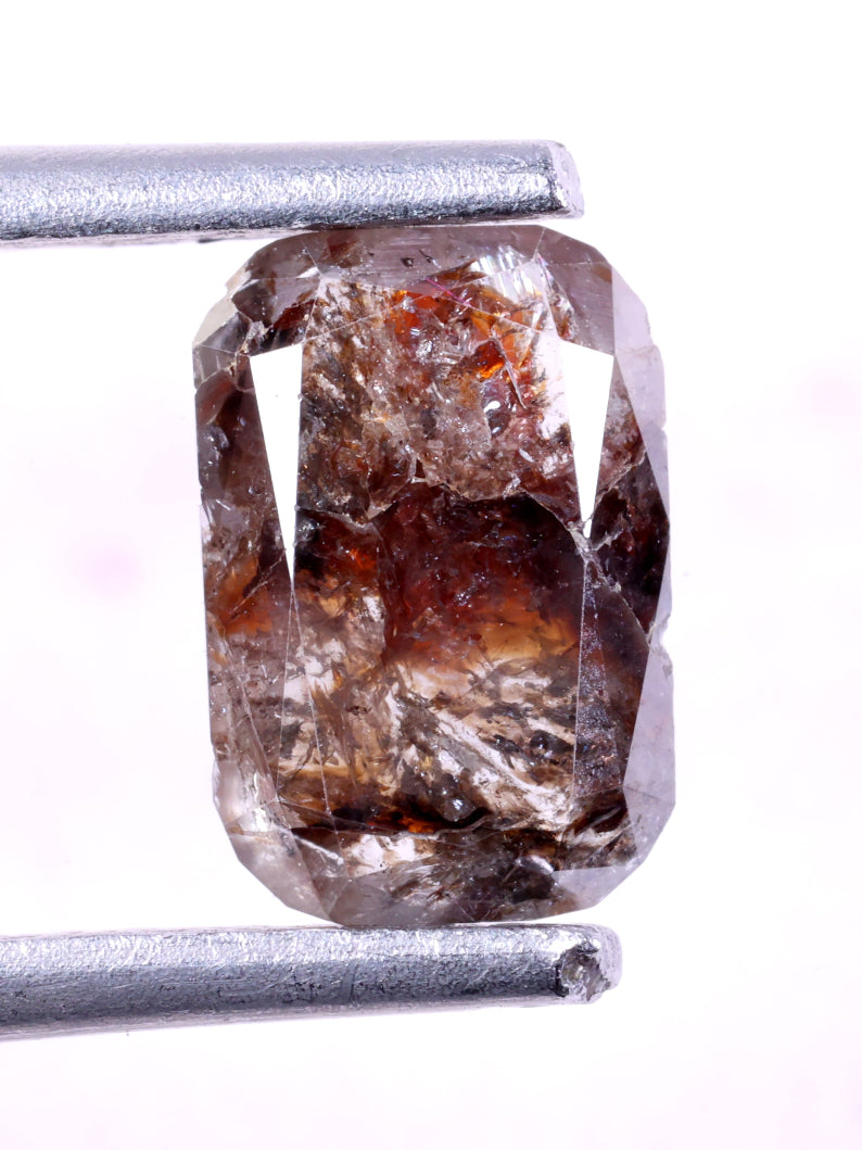 Brown diamond held by tweezers on a white background