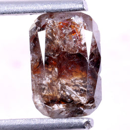 Brown diamond held by tweezers on a white background