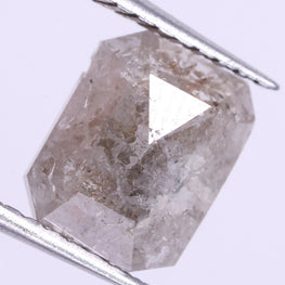 loose diamond held between tweezers on a light purple background