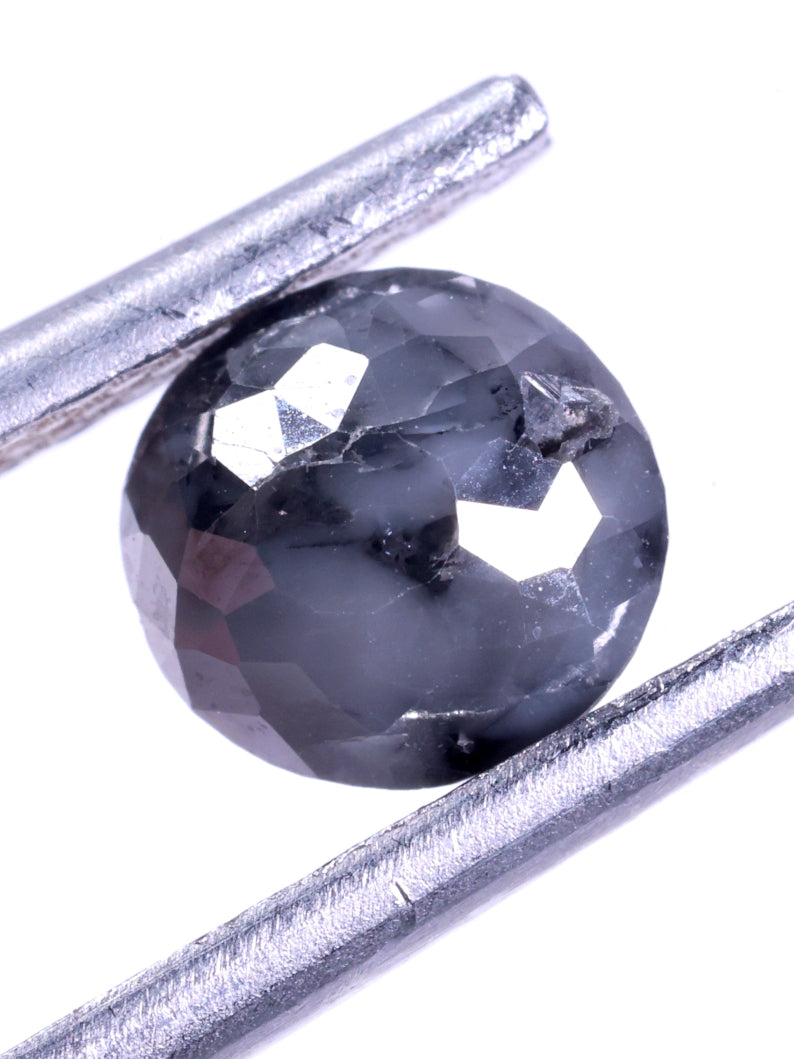 Faceted dark grey diamond held between two metal sticks on a white background