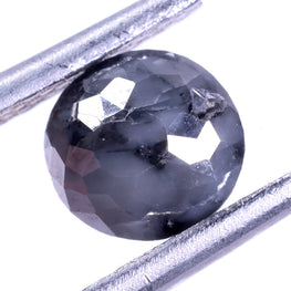 Faceted dark grey diamond held between two metal sticks on a white background