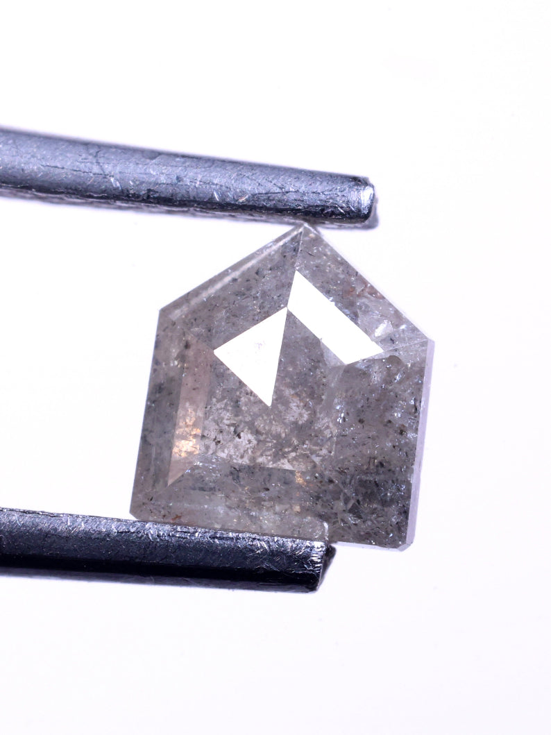 Bullet cut diamond held between tweezers on a white background