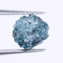 Blue diamond held between tweezers on a white background