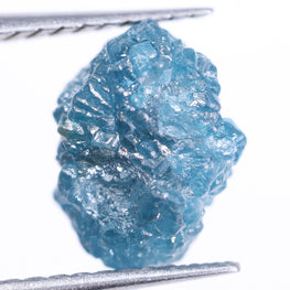 Raw blue diamond held by tweezers on a white background