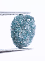 Raw blue diamond held by tweezers on a white background