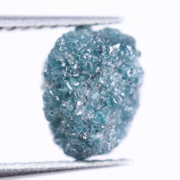 Raw blue diamond held by tweezers on a white background