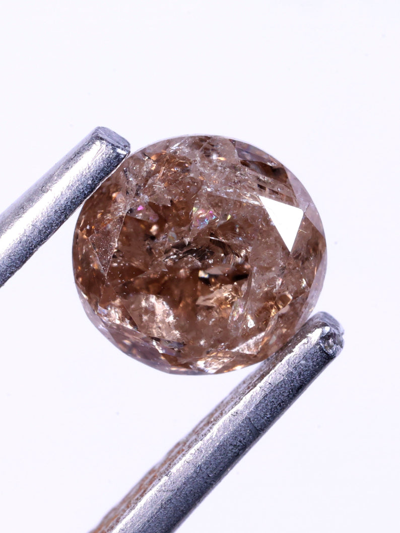 Brown diamond held by tweezers on a white background