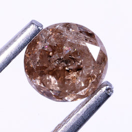 Brown diamond held by tweezers on a white background