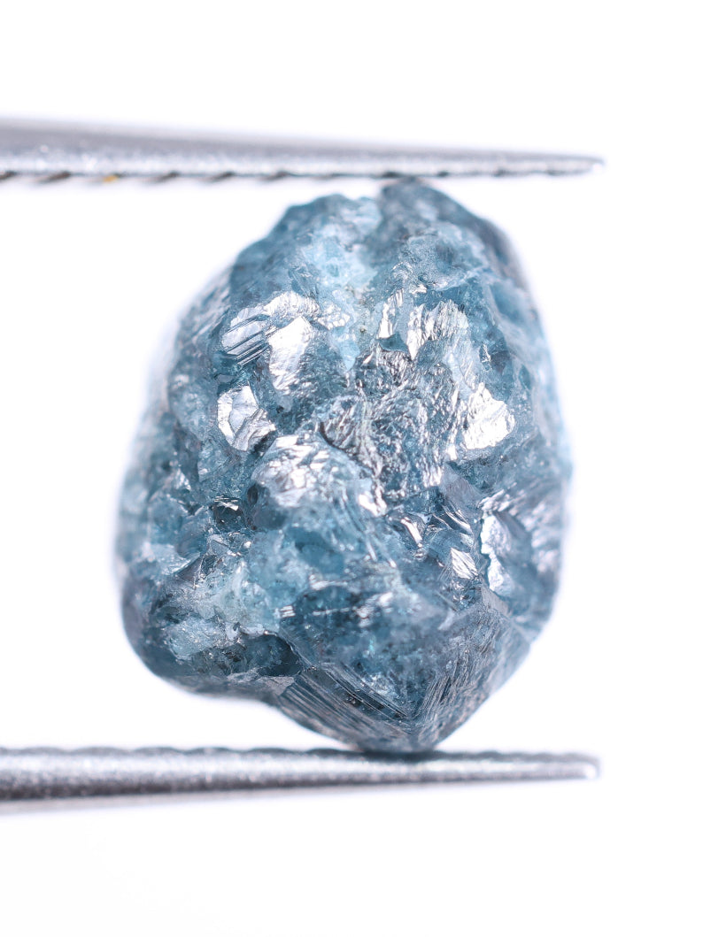 Raw diamond held between two metal rods on a white background