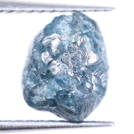 Raw diamond held between two metal rods on a white background