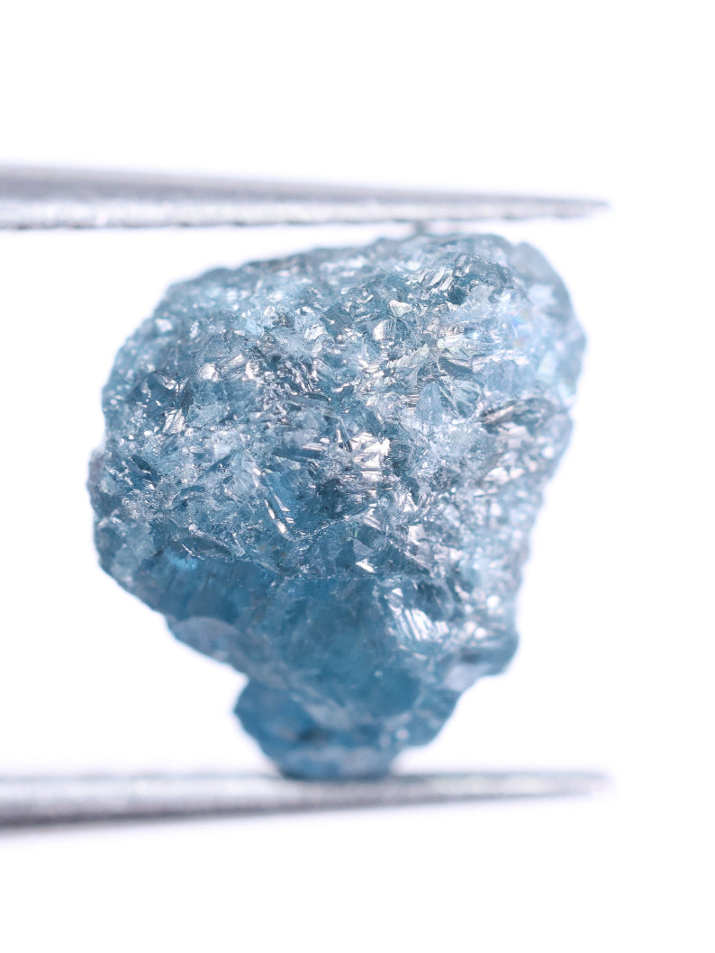 Raw blue diamond held by tweezers on a white background