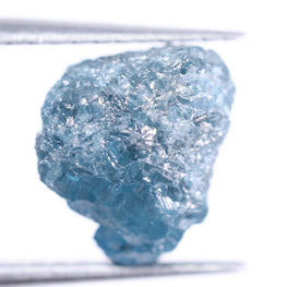 Raw blue diamond held by tweezers on a white background