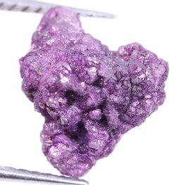 Purple diamond on tweezers against a white background
