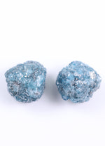 Pair of blue glittery stud earrings on a white background