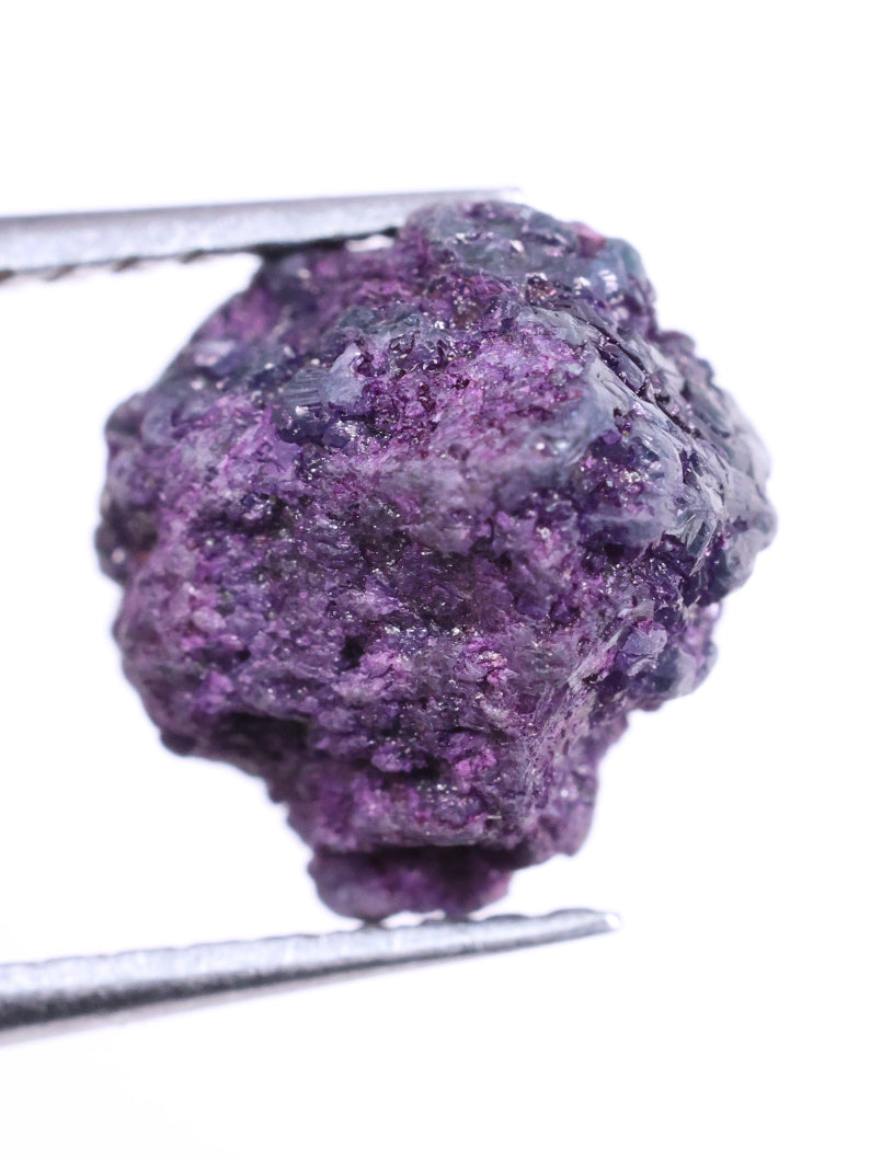 Purple diamond held by tweezers on a white background