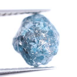 blue rough diamond held by tweezers on a white background
