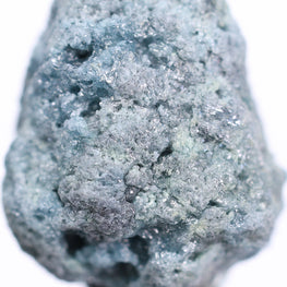 Raw blue stone held by tweezers on a white background