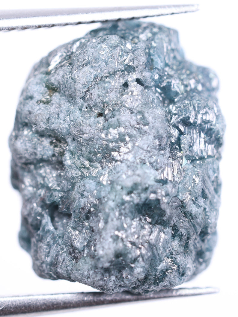 Raw diamond held by tweezers on a white background