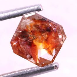 red natural diamond held by tweezers on a white background