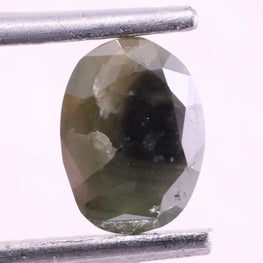 Green diamond held between tweezers on a white background