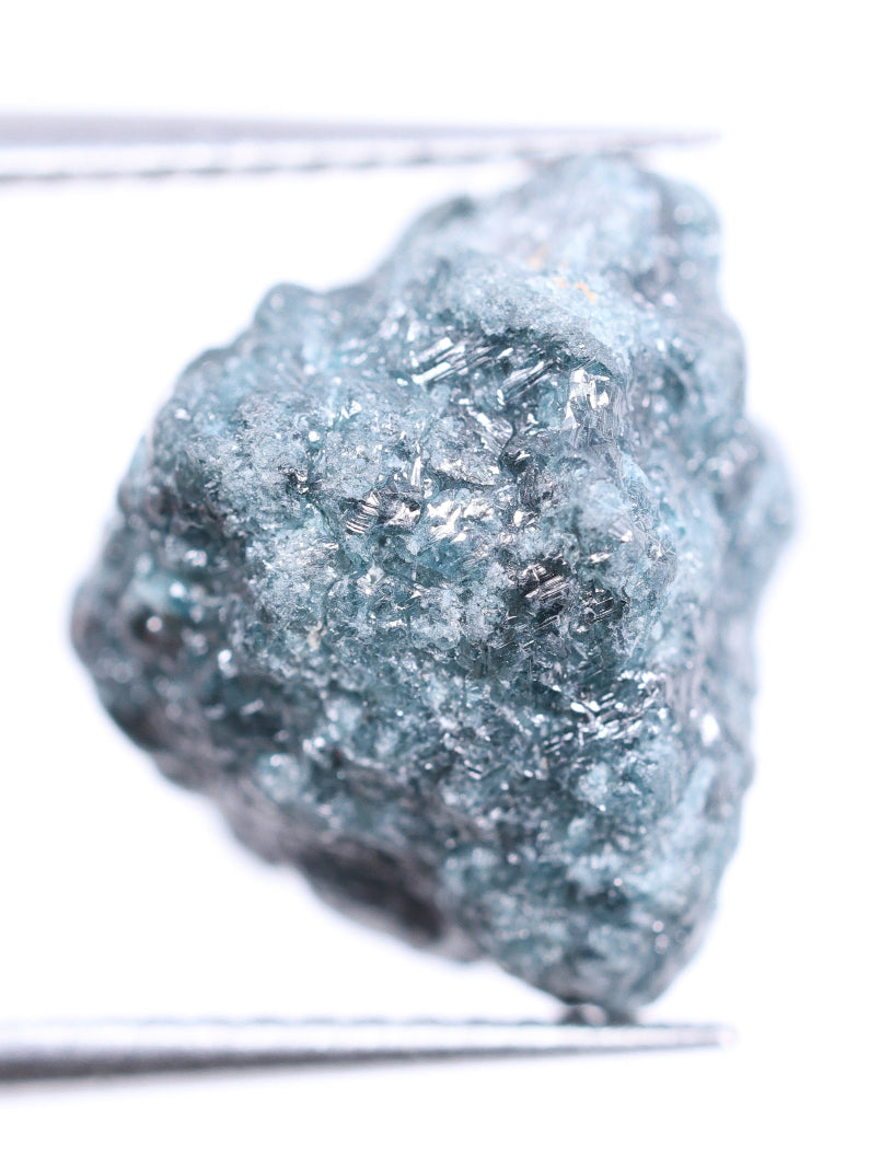 Raw diamond held by tweezers on a white background