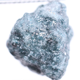 Raw diamond held by tweezers on a white background