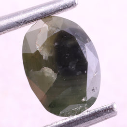 Green diamond held by tweezers on a white background