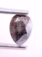 Brown diamond held between two metal prongs on a white background