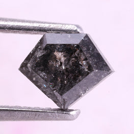 Shield diamond held by tweezers on a light pink background