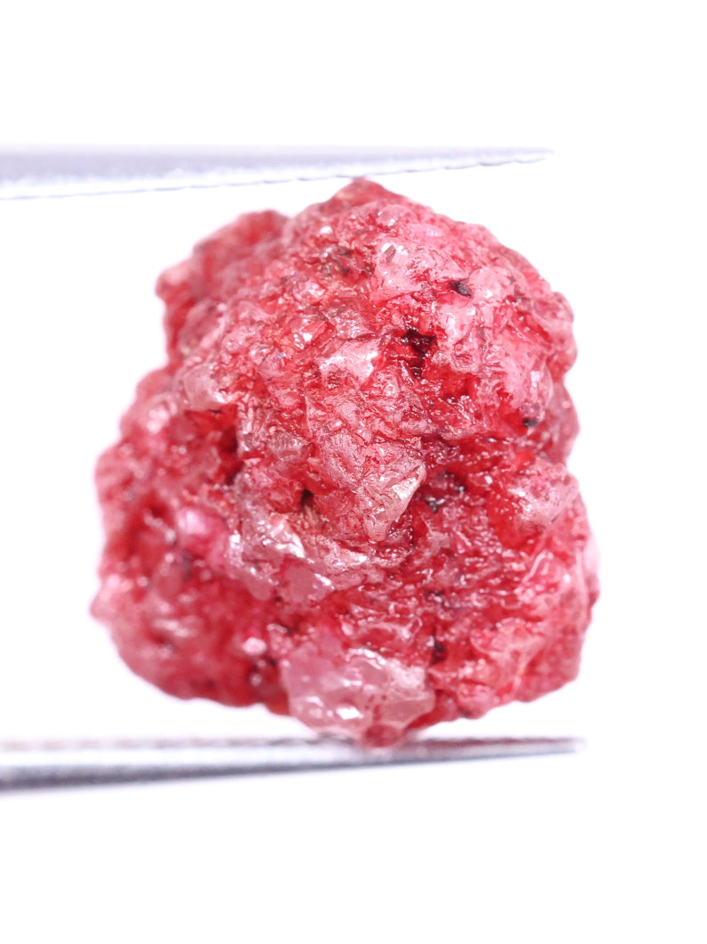 Close-up of a pink diamond rock held by tweezers on a white background