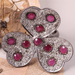 Butterfly-shaped jewelry piece with pink stones on a leaf background