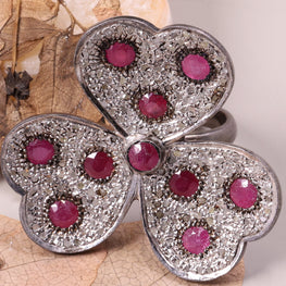 Silver brooch with red gemstones on a leafy background