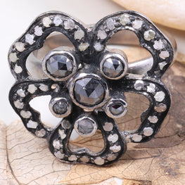 Silver flower-shaped brooch with gemstones on a leafy background