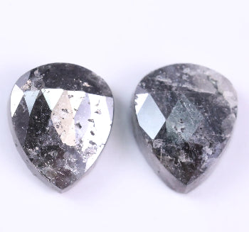 Two teardrop-shaped diamond with a dark, textured surface on a white background