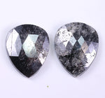 Two pear-shaped diamond with a metallic sheen on a white background