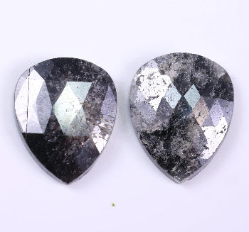 Two pear-shaped diamond with a metallic sheen on a white background