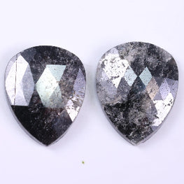 Two pear-shaped diamond with a metallic sheen on a white background