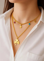 Gold necklace with various charms on a white shirt natural diamonds