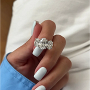 Three-stone oval diamond engagement ring in white gold on a woman’s hand with light blue manicure