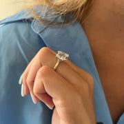 Three-stone oval diamond engagement ring in white gold on a woman’s hand with light blue manicure