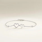 Silver bracelet with two heart charms on a light beige background